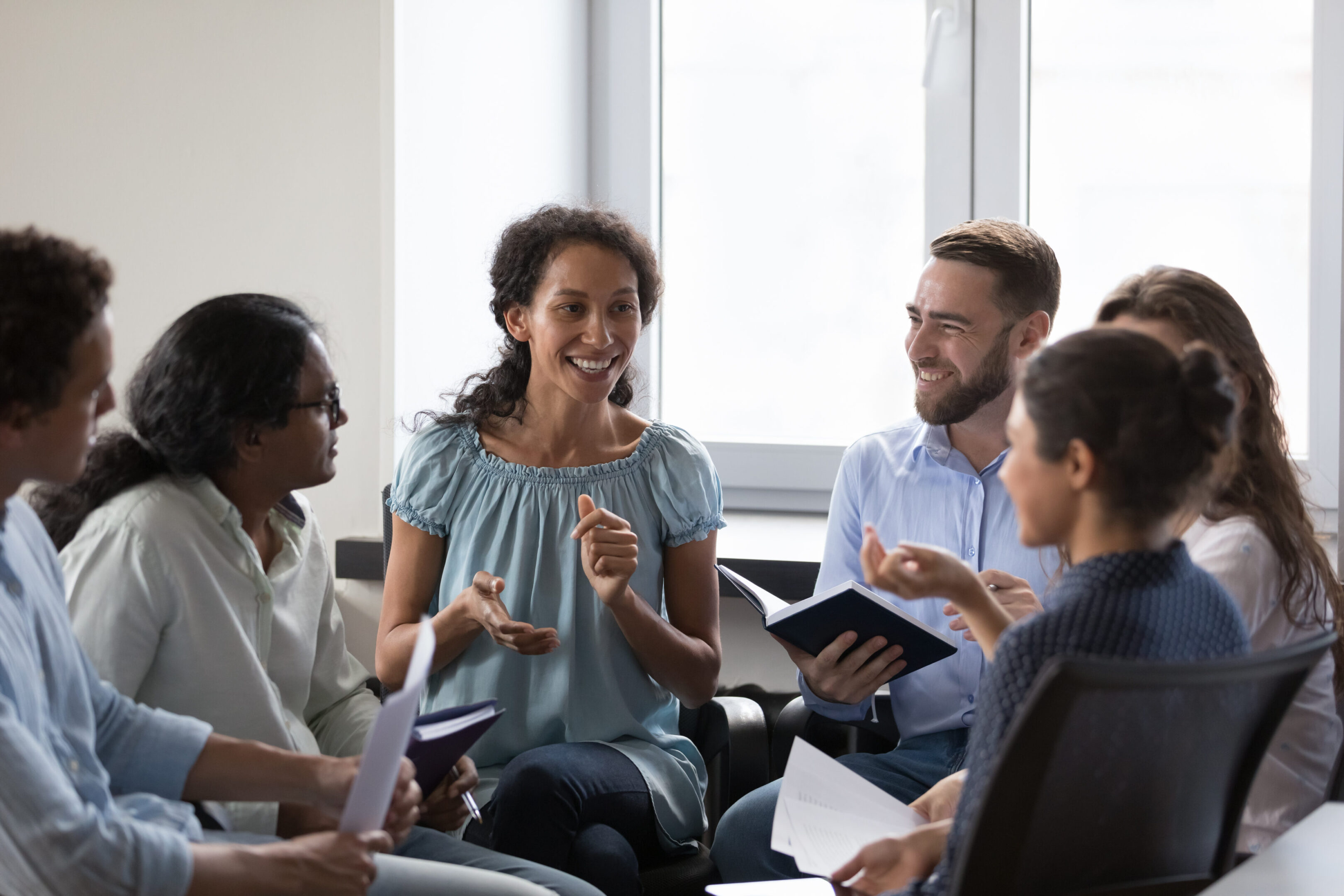 Happy diverse addicts sitting on chairs in circle, talking